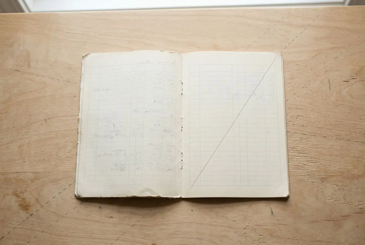 Carnet ouvert posé sur une table en bois, pages vierges avec une ligne diagonale tracée sur le droit. convention collective travail temporaire permanent grille salaire 2026